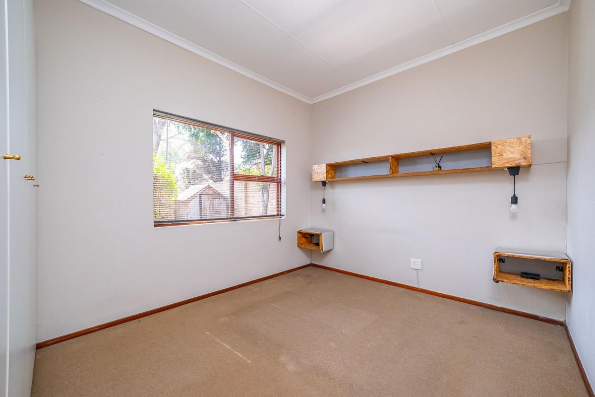 An empty bedroom featuring neutral walls, carpet flooring, and custom built-in wooden shelving units.