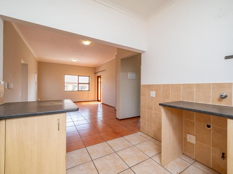 Open-plan kitchen and living area featuring tiled flooring, laminate cabinetry, and neutral wall finishes, offering a functional and versatile living space.