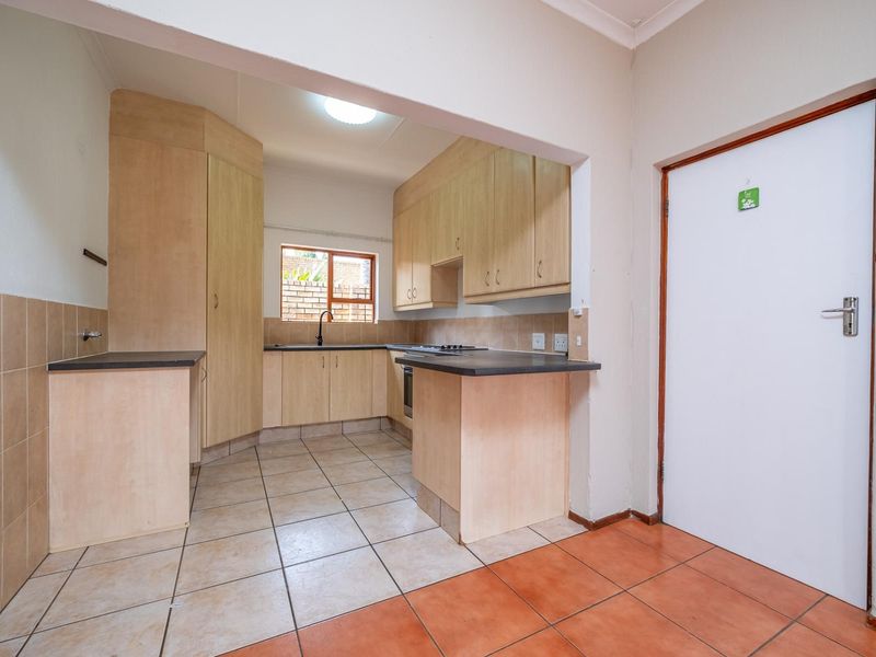 A functional kitchen featuring laminate cabinetry, dark countertops, built-in cooking appliances, and tiled flooring, offering a clean and practical layout.