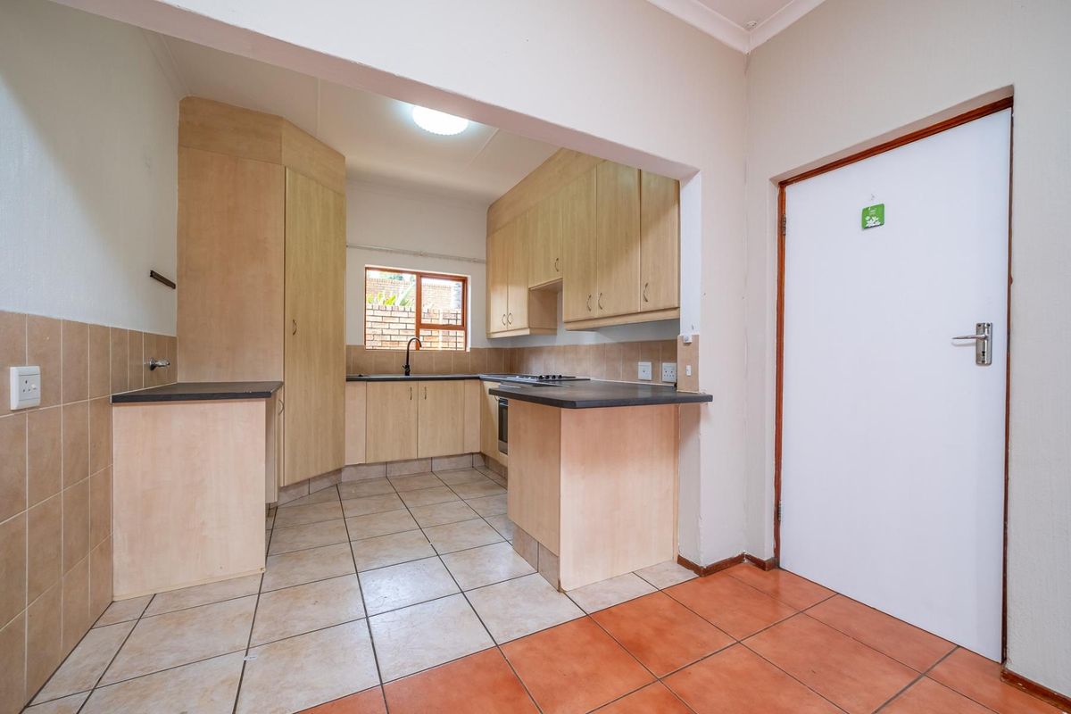 A functional kitchen featuring laminate cabinetry, dark countertops, built-in cooking appliances, and tiled flooring, offering a clean and practical layout.