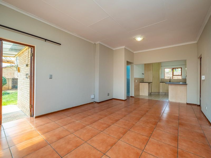 An open-plan living area featuring tiled flooring and direct access to the garden, flowing into a functional kitchen space.