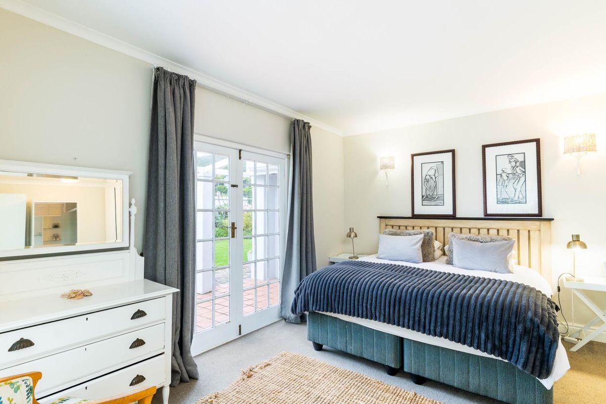A well-maintained bedroom featuring neutral walls, coving, and direct access to the garden through white-framed French doors.