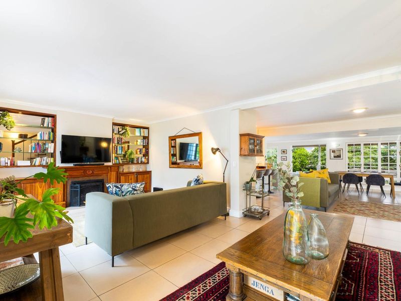 Spacious open-plan living and dining area featuring tiled floors, a built-in fireplace with shelving, and large sliding doors leading to the garden.