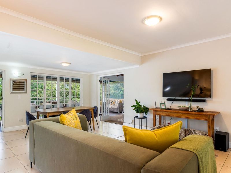 Spacious open-plan living and dining area featuring neutral tiled flooring, coved ceilings, and direct access to the outdoor patio through classic french doors.