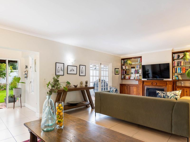 Spacious living room featuring tiled flooring, a classic fireplace with built-in wooden cabinetry, and direct access to the garden through french doors.