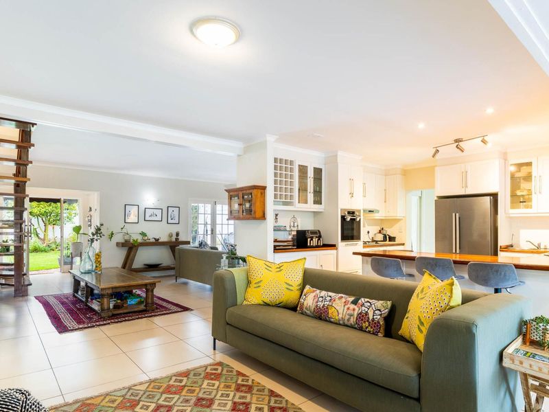 Spacious open-plan living area featuring a modern kitchen with island, tiled floors, and a distinctive wooden staircase leading to the upper level.