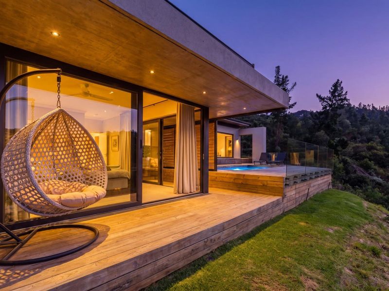 Modern outdoor timber deck featuring a glass balustrade, recessed lighting, and seamless access to a swimming pool with scenic views.