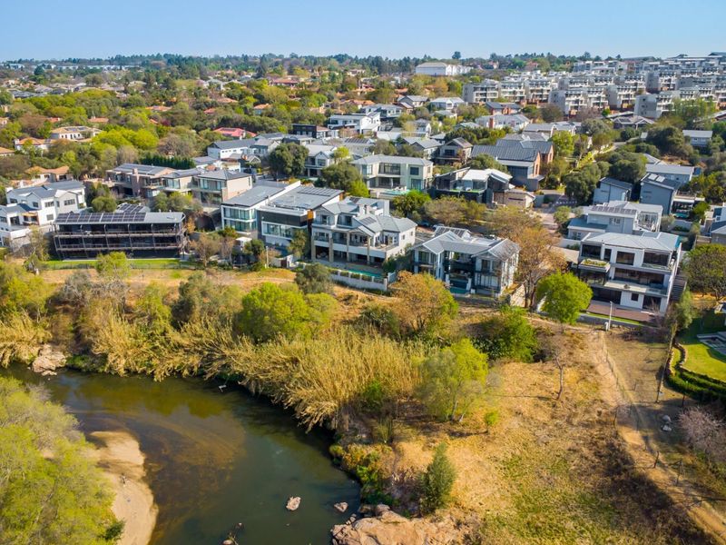 An aerial view of a residential estate situated along a river, showcasing the surrounding landscape and neighborhood layout.