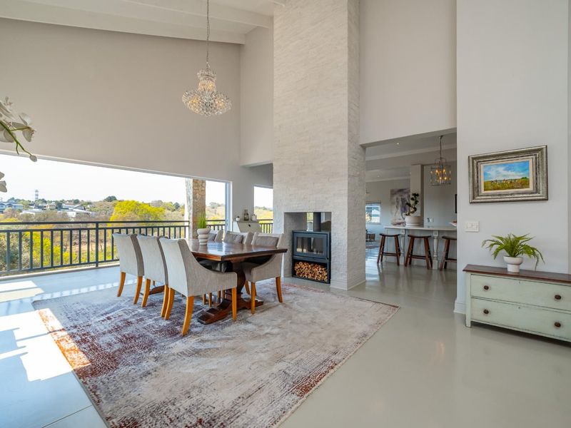Spacious open-plan living and dining area featuring a striking double-sided fireplace, high ceilings, and seamless access to a balcony with scenic views.