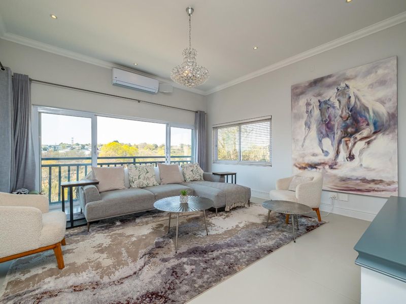 Bright and modern living room featuring large sliding glass doors with balcony access, split-system air conditioning, and elegant chandelier lighting.