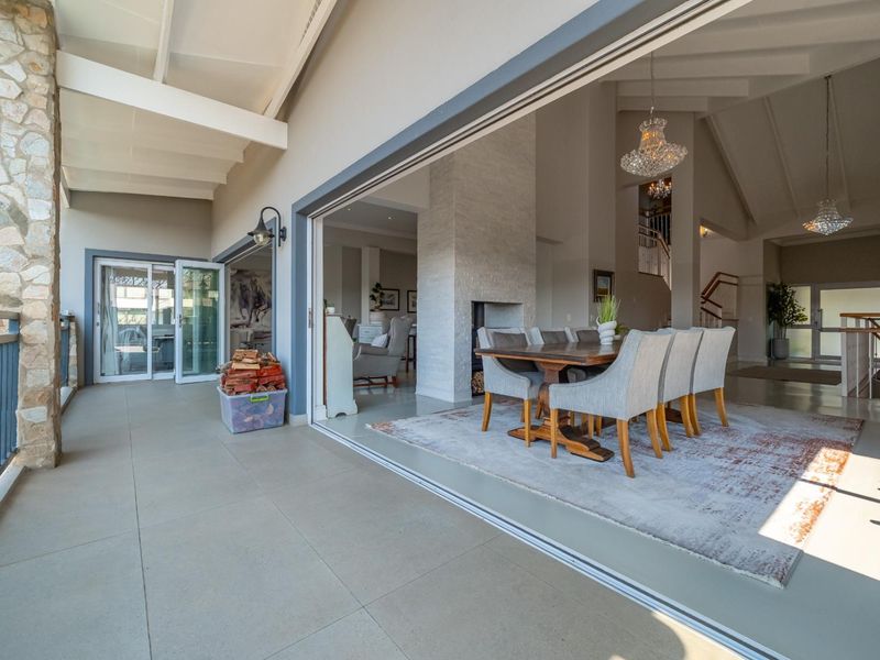 Spacious covered patio featuring stone pillar detailing and seamless flow into the open-plan dining and living area through large sliding glass doors.