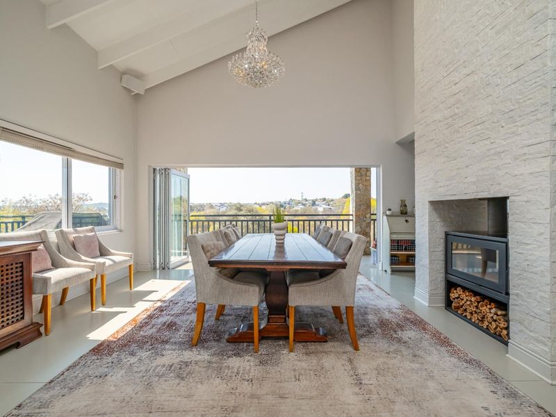 Spacious dining room featuring a vaulted ceiling, a striking stone-clad built-in fireplace, and large stacking doors opening to an outdoor balcony with scenic views.