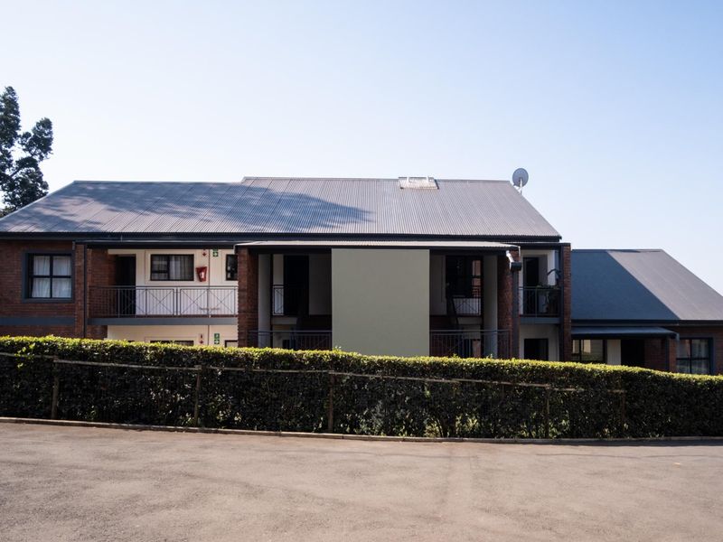 A view of the apartment building exterior featuring a corrugated metal roof, brick facade, and balcony access.