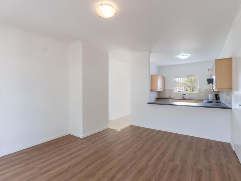 Open plan living area featuring laminate flooring and a functional kitchen with built-in cabinetry and a breakfast bar.