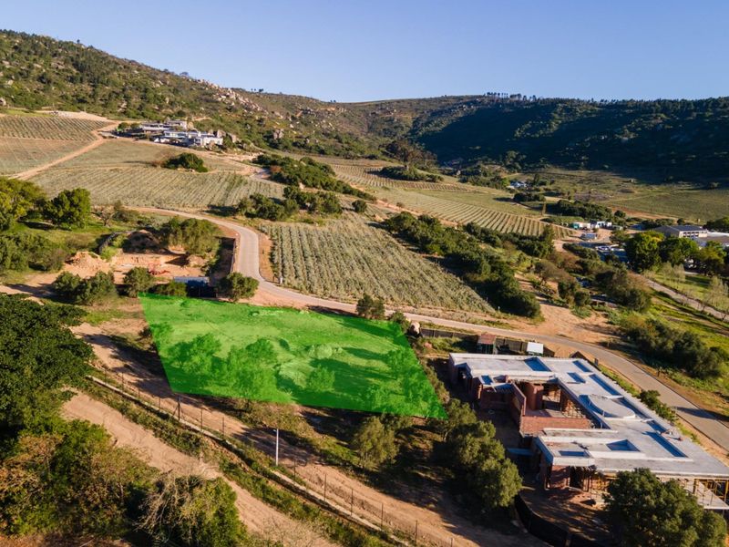Aerial view of a vacant residential plot situated in a scenic rural landscape with surrounding vineyards and established access roads.