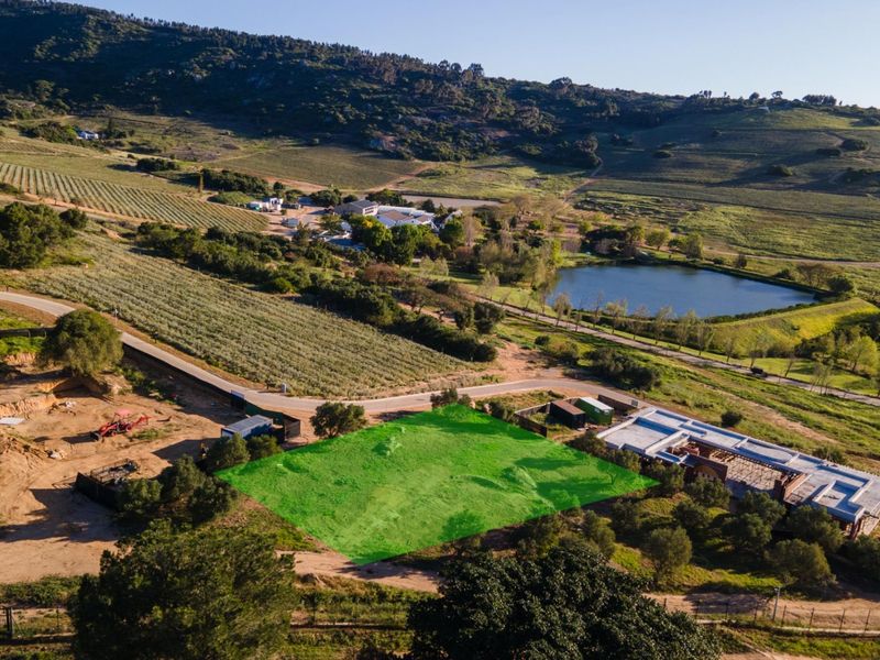 Aerial view of a vacant residential plot situated within a scenic rural landscape, featuring surrounding vineyards and a nearby lake.