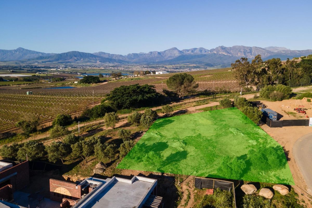 An aerial view of a vacant residential plot with scenic mountain and vineyard views in the surrounding area.
