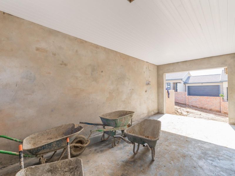 An unfinished garage space featuring raw plastered walls, a concrete floor, and a white tongue and groove ceiling, currently in a construction phase.