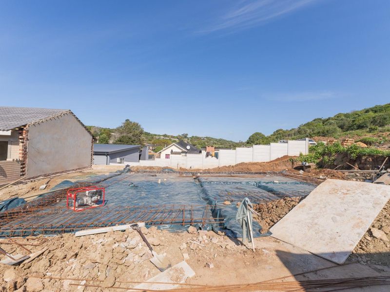 A construction site view showing a prepared concrete foundation slab with reinforcing steel mesh, ready for further building development.