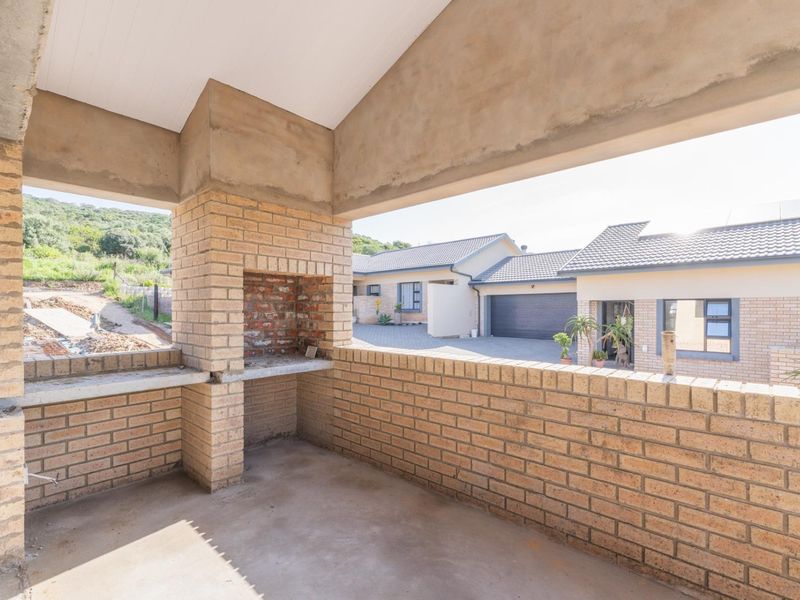 Covered patio area featuring a built-in brick braai, concrete flooring, and exposed structural elements, offering a blank canvas for outdoor entertainment space development.