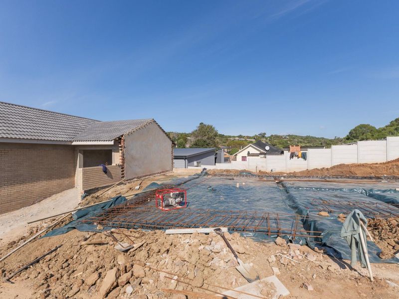A construction site view showing the foundation preparation with reinforcing steel mesh and damp proofing membrane laid out for a new building extension.