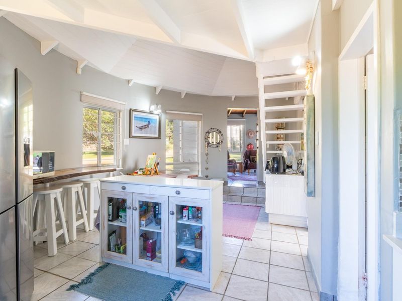 Open plan living area featuring tiled flooring, exposed beam ceiling, a breakfast bar, and a staircase leading to an upper level.