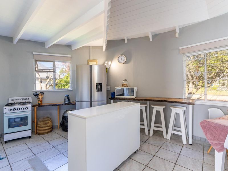 A functional kitchen featuring tiled flooring, exposed beam ceilings, a gas stove, and a built-in breakfast bar with natural light.