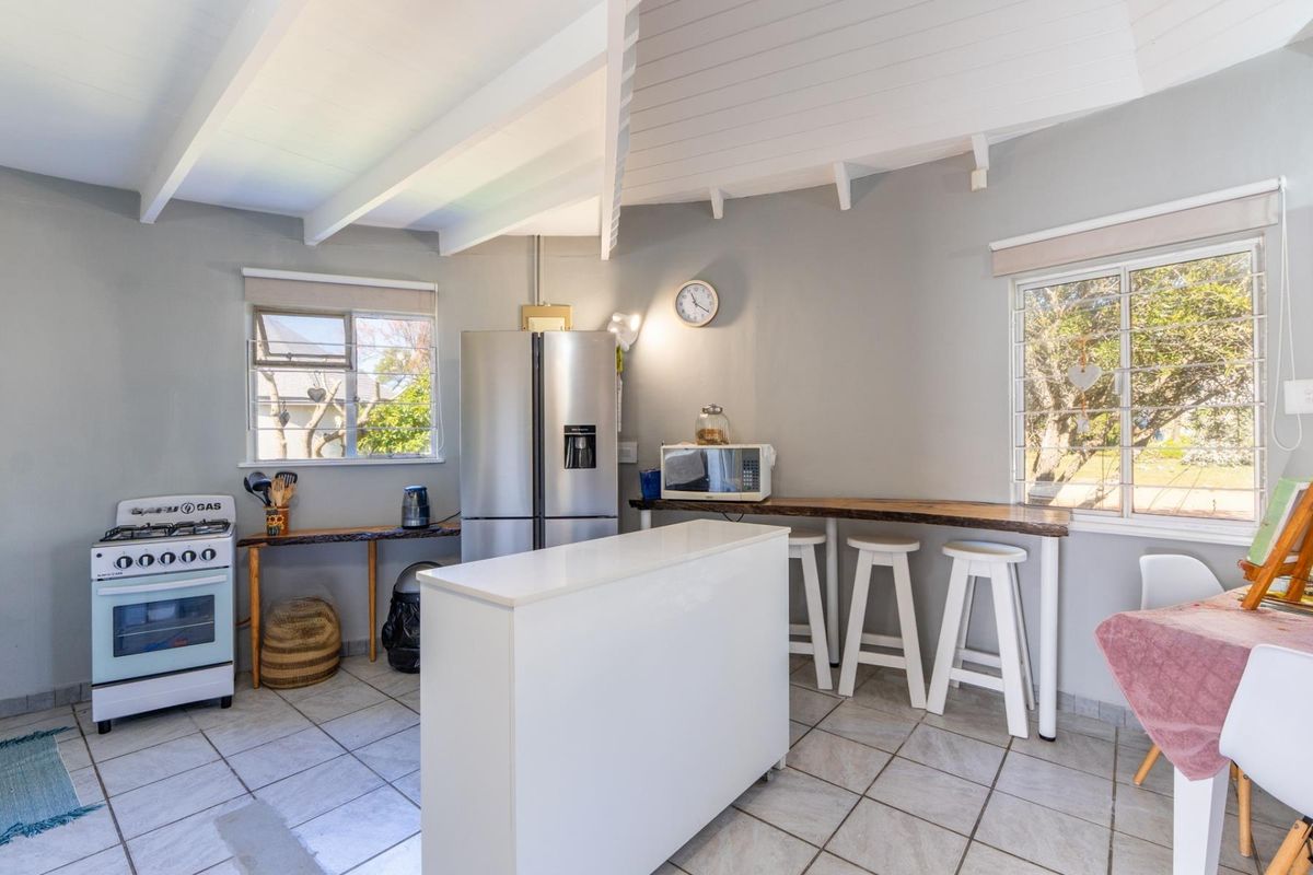 A functional kitchen featuring tiled flooring, exposed beam ceilings, a gas stove, and a built-in breakfast bar with natural light.