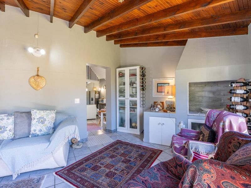 Cozy living room featuring a high exposed timber beam ceiling, tiled flooring, and a built-in fireplace, creating a warm and inviting atmosphere.