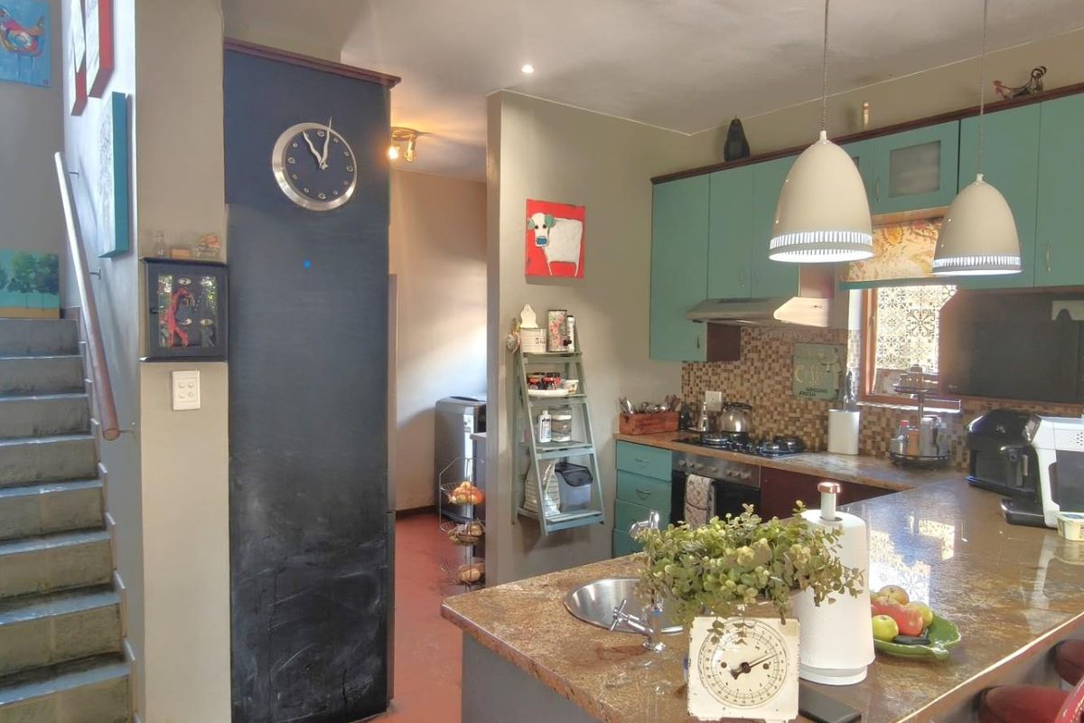 A functional kitchen featuring stone countertops, built-in cabinetry, and a gas hob, adjacent to an internal staircase.