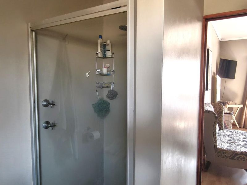 A functional bathroom featuring a glass-enclosed shower with chrome fixtures, providing a clean and practical space adjacent to the bedroom.