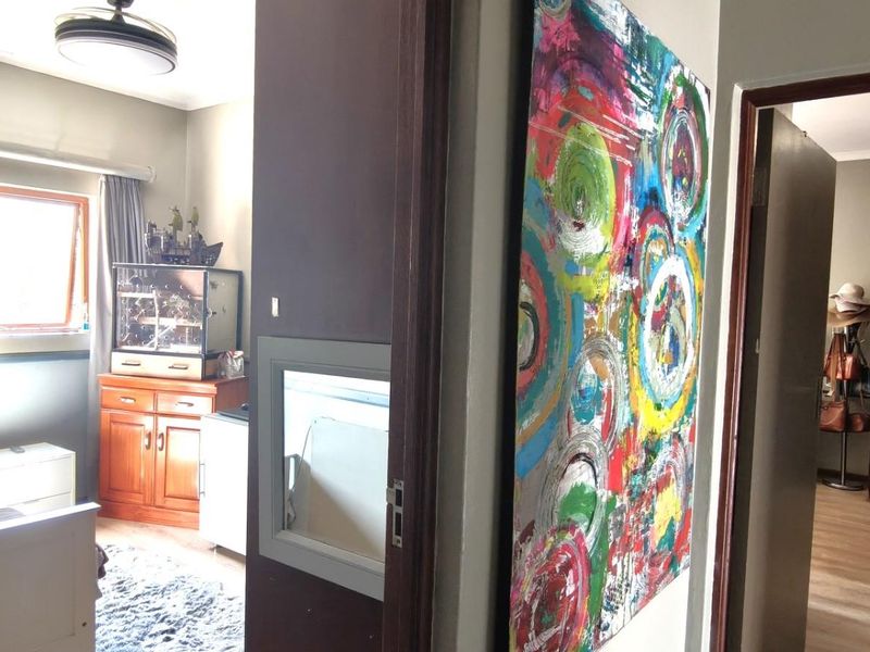 A view from a hallway looking into a bedroom and a secondary room featuring built-in cupboards and laminate flooring.