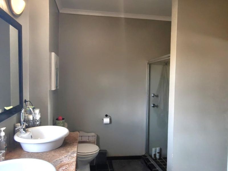 A functional bathroom featuring a double vanity with vessel sinks, stone countertop, a separate shower enclosure, and tiled flooring.
