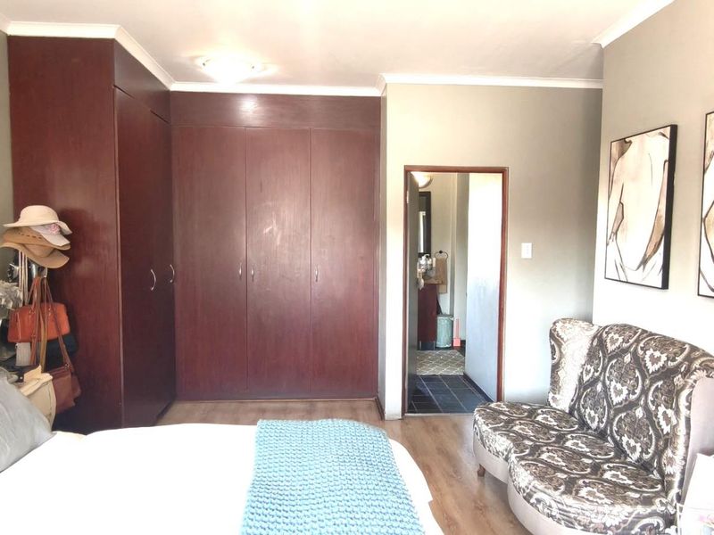 A bedroom featuring built-in dark wood cupboards, laminate flooring, and direct access to an en-suite bathroom.
