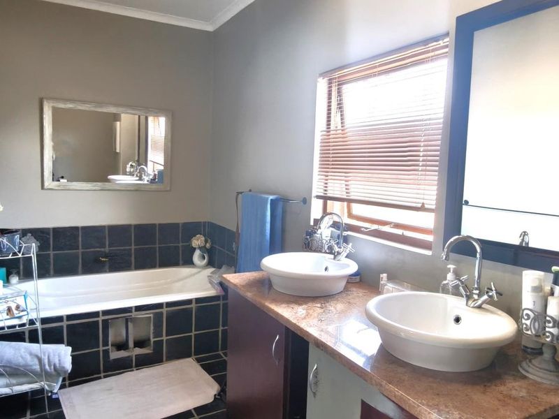 A functional bathroom featuring a built-in bathtub with tiled surround, a double vanity with vessel sinks, and natural light from a window.