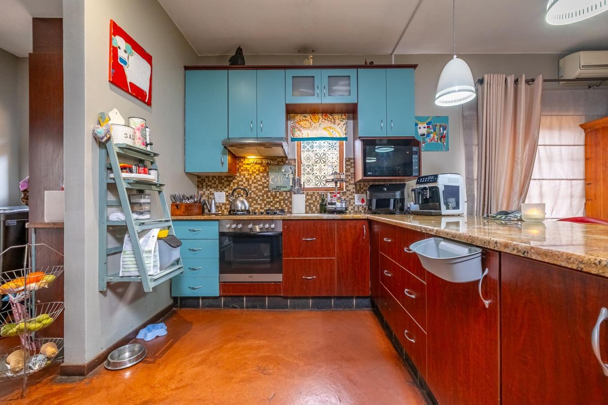 A functional kitchen featuring two-tone cabinetry, granite countertops, a built-in oven and hob, and a tiled backsplash.