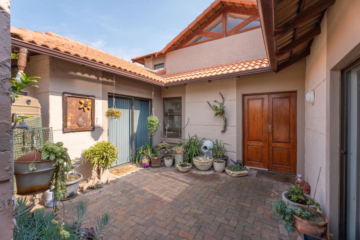 A private brick-paved courtyard featuring terracotta roof tiles, exposed timber trusses, and double wooden entrance doors, providing a charming outdoor transition space.