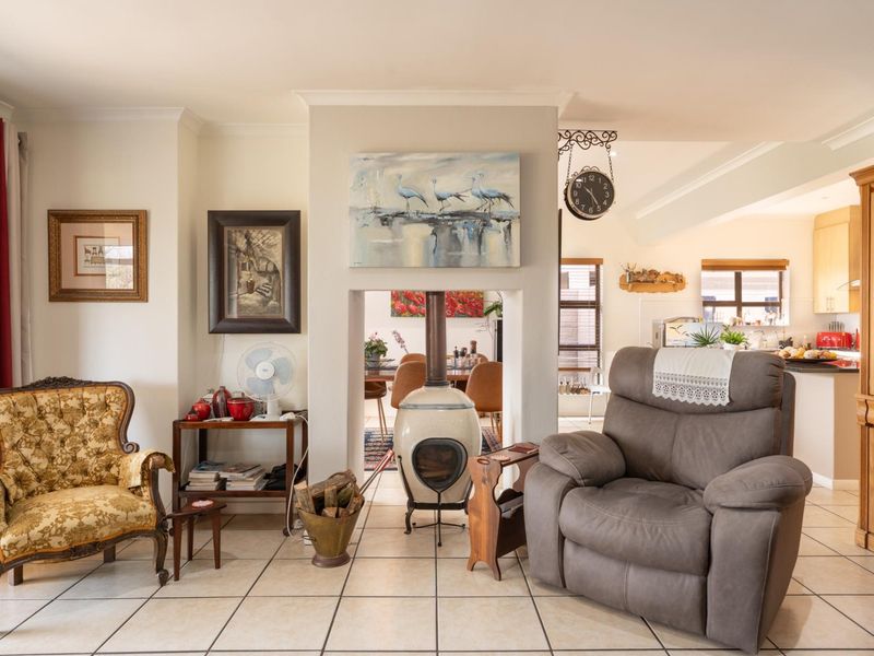 Open-plan living area featuring tiled flooring, a central freestanding fireplace, and a connected kitchen space with built-in cabinetry.