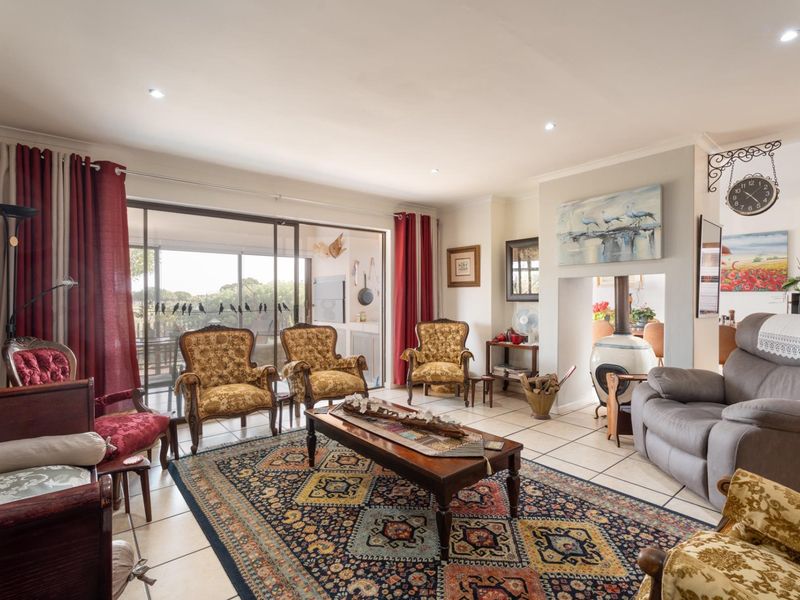 Spacious living room featuring tiled flooring, recessed lighting, and a central fireplace, with large sliding doors providing access to the outdoor patio area.