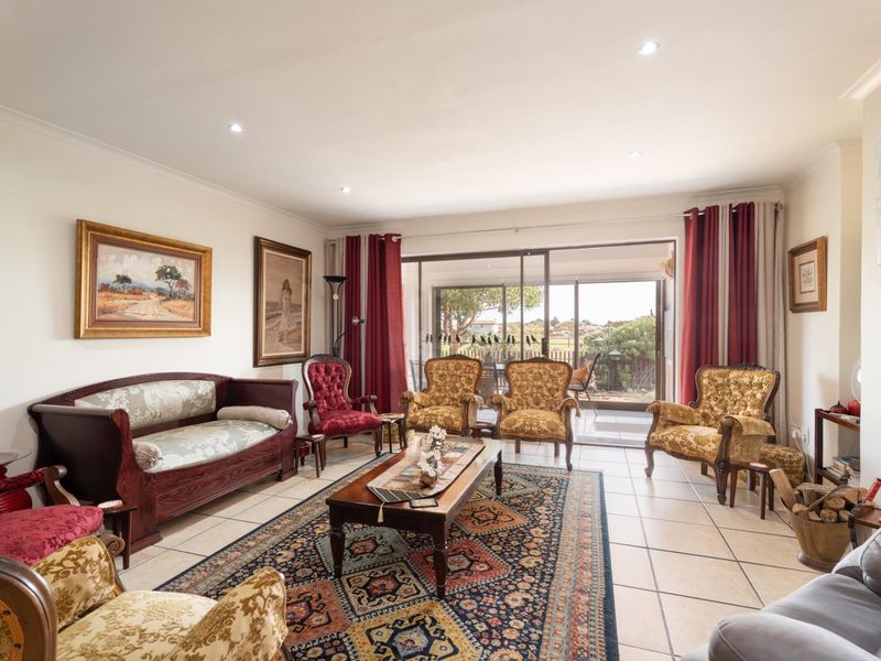 Spacious living room featuring tiled flooring, recessed downlights, and large sliding glass doors providing seamless access to the outdoor patio area.