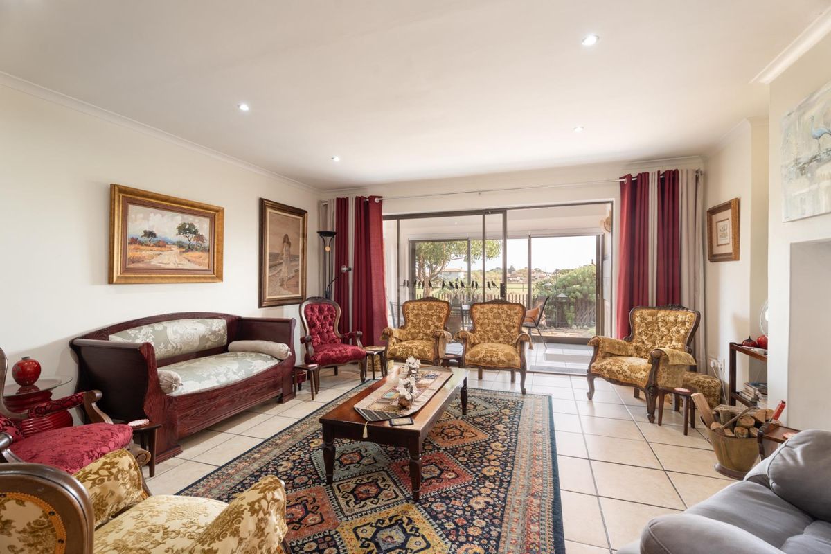 Spacious living room featuring tiled flooring, recessed downlights, and large sliding glass doors providing seamless access to the outdoor patio area.
