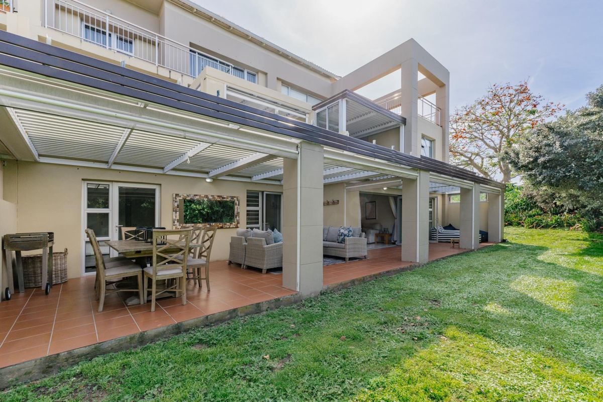 Spacious covered rear patio with tiled flooring, providing seamless indoor-outdoor flow to the garden area of this apartment complex.