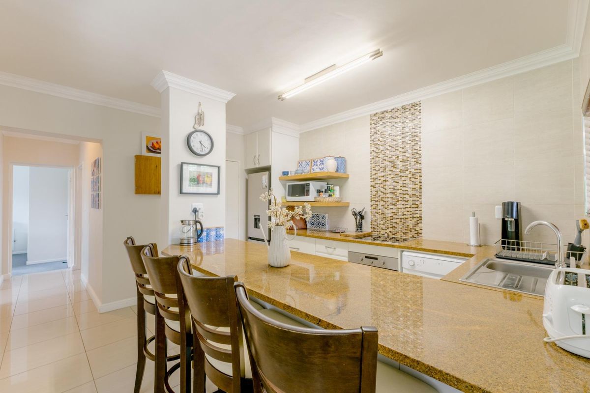 A well-maintained kitchen featuring granite countertops, mosaic tile backsplash, integrated appliances, and ceramic floor tiles with a breakfast bar layout.