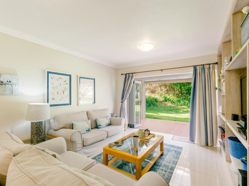 Bright living room featuring tiled flooring, built-in shelving, and sliding glass doors providing direct access to a private patio and garden area.