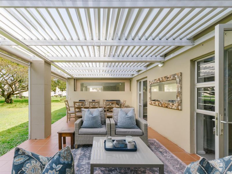 A spacious covered patio featuring a modern louvred roof, tiled flooring, and direct access to the garden through sliding glass doors.
