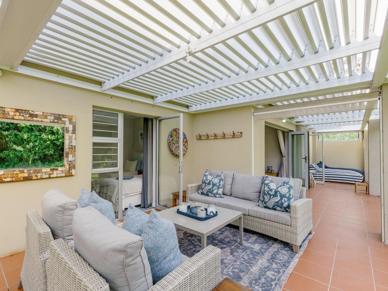 A spacious covered patio featuring a louvred pergola roof, tiled flooring, and direct access to interior living spaces through sliding glass doors.