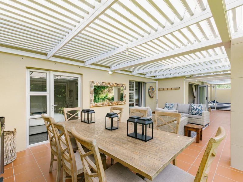 Spacious covered patio featuring a slatted pergola roof and tiled flooring, providing a seamless transition between indoor and outdoor living areas.