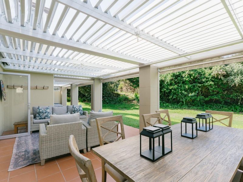 Spacious covered patio featuring a white louvred roof, tiled flooring, and direct access to the garden through sliding glass doors.