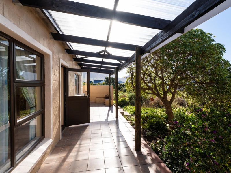 A covered outdoor patio featuring tiled flooring and a timber pergola structure, providing a seamless transition to the adjacent garden area.