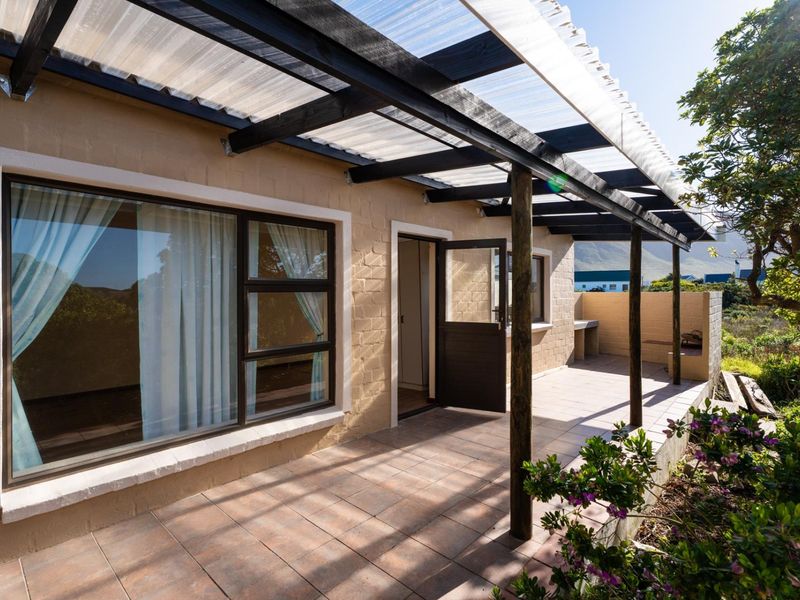 A covered outdoor patio featuring tiled flooring, a timber pergola with a translucent roof, and a built-in masonry counter area.